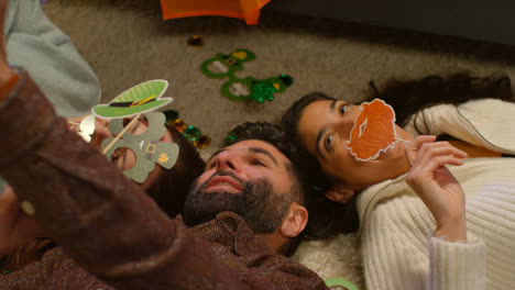 Group-Of-Friends-Dressing-Up-At-Home-Lying-On-Floor-Celebrating-At-St-Patrick's-Day-Party-Posing-For-Selfie-On-Phone